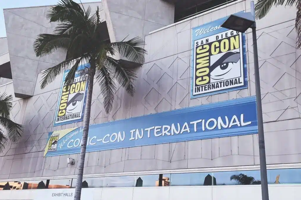 Exterior view of San Diego Comic-Con venue with banners and palm trees.